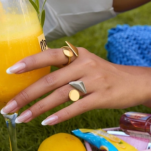 Modern geometric gold and silver rings styled in a sunny outdoor picnic setting