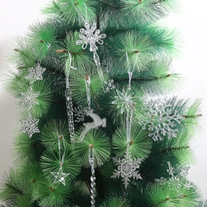 Set of clear acrylic Christmas ornaments like deer and snowflakes on green pine tree branches