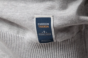 Détail de l'étiquette bleu marine sur le pull en maille grise texturée pour hommes