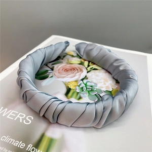 Close-up of a grey pleated satin headband with a French retro twisted design on a book