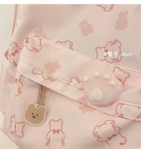 Detail of pink backpack with bear prints, plush paw decor, and cute bear head keychain