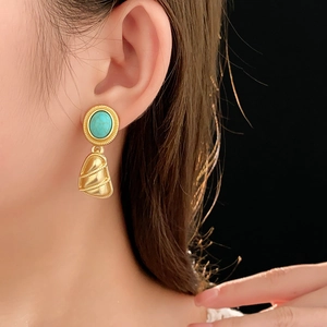 Détail de boucles d'oreilles vintage en or avec turquoise ovale et pendentif coquillage