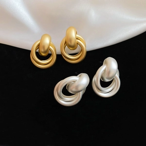 Detailed macro view of interlocking matte gold and silver geometric stud earrings
