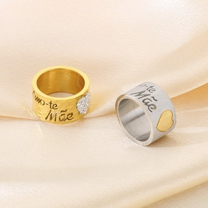 Detail of gold and silver stainless steel rings with Amo-te Mãe engraving and heart