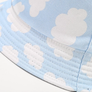 Blue reversible canvas bucket hat featuring white cloud patterns and stitching details