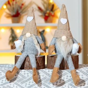 Detail of knit heart hat gnomes on wooden stand with warm indoor background