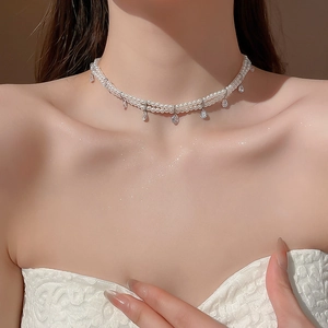 Detail of double-layer pearl necklace with teardrop zircon pendants on model's neck