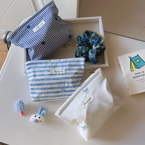 Detailed view of blue striped and plaid cotton makeup bags with delicate bow embroidery
