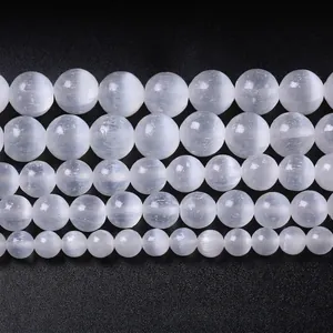 Macro detail of white selenite round beads in five various sizes on black background