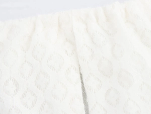 Detailed macro view showing the soft white knit fabric and diamond mesh pattern of the dress