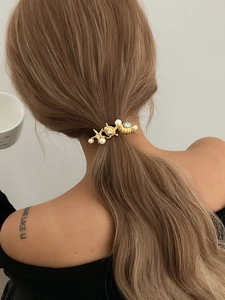Detail of gold starfish and shell hair clip with pearls and rhinestones on ponytail
