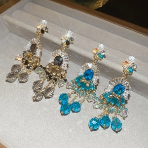 Dettaglio di orecchini barocchi con cristalli e perle su vassoio in velluto grigio