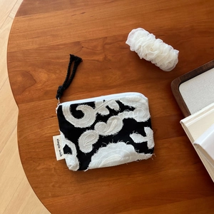 Detail shot of boho linen pouch featuring white embroidery on a dark wooden surface