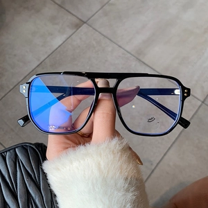 Dettaglio occhiali vintage a doppio ponte con lenti anti-luce blu e borchie dorate lucide