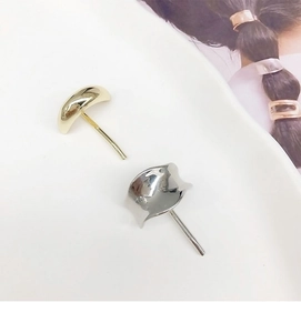 Close-up of gold and silver irregular curved metal hair hooks on white ceramic plate