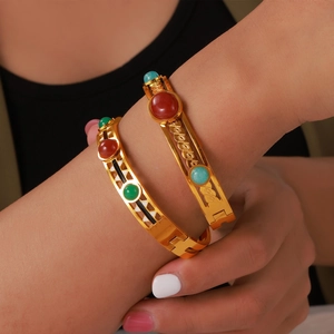 Vintage hollow gold-plated titanium bracelet with colorful stone inlays on model's wrist