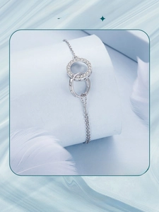 Detail of interlocking silver rings with pave crystals and heart cutout on delicate chain