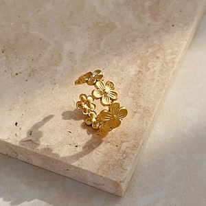Fashionable 18K gold stainless steel flower open ring displayed on beige stone