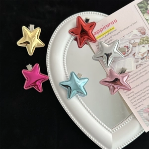 Colorful star-shaped leather hair clips in metallic gold, red, and blue on a mirror