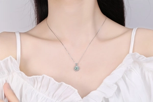 Close-up of a s925 silver necklace with a green moissanite pendant in halo setting