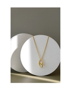 Detail of minimalist gold double-ring heart necklace on white stone podium background