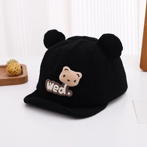 Détail du bonnet bébé en velours côtelé noir avec oreilles d'ours 3D et écusson peluche