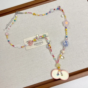 Close-up of colorful beaded necklace with floral glass beads and a ceramic peanut pendant
