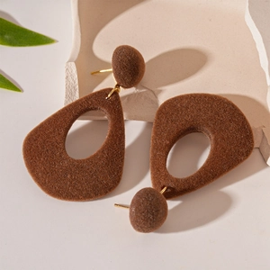 Boucles d'oreilles goutte irrégulières en feutrine marron sur un socle en pierre