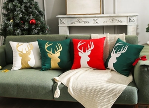 Set of 4 Christmas pillow covers with reindeer and tree embroidery on a cozy sofa