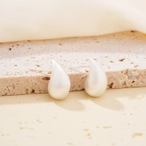 Minimalist matte silver water drop stud earrings displayed on natural stone texture