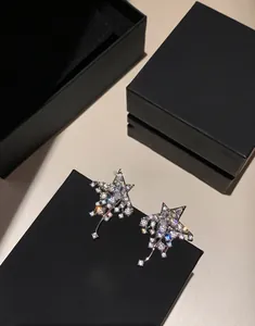 Close-up of sparkling star zirconia earrings with silver needles and black gift box