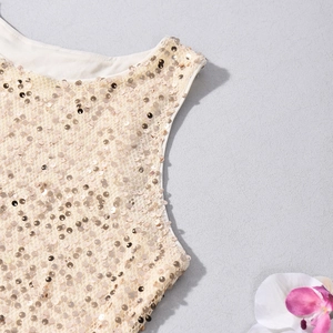 Détail des paillettes dorées champagne sur l'encolure d'une robe de soirée moulante