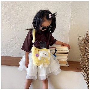Detail of yellow plush children handbag with 3D teddy bear worn by child model