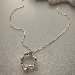 Minimalist 925 sterling silver necklace with irregular geometric ring pendant on a neutral surface