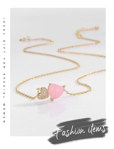 Detailed macro view of gold-plated double heart pendant with pink resin and pavé stones