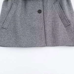 Detail of gray wool blend coat featuring symmetrical pockets and dark button closure