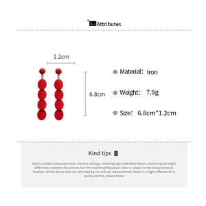 Detail view of red geometric disc earrings with precise size dimensions and iron material specs