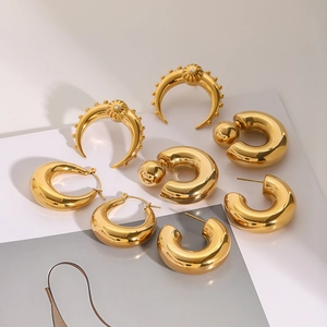 Flat lay of multiple golden stainless steel hoop and crescent stud earrings with zircon