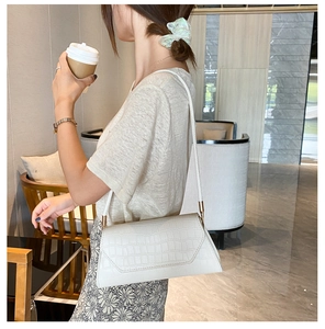 White faux crocodile leather baguette bag with flap cover shown on a model's shoulder