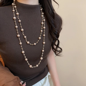 Close-up of double-layer French pearl and crystal necklace worn on a brown sweater
