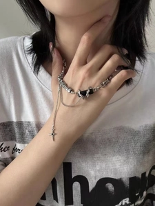 Detail of layered titanium steel necklace with black gemstone and cross pendant on model