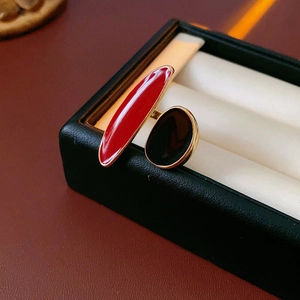 Close-up of gold open ring with red and black enamel geometric inserts on display