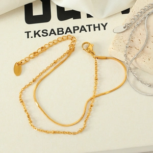 Minimalist double-layered gold snake and bead chain bracelet on a white silk background