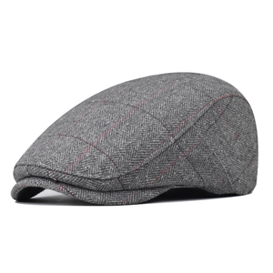 Close-up of grey herringbone fabric with red windowpane check on a classic flat cap