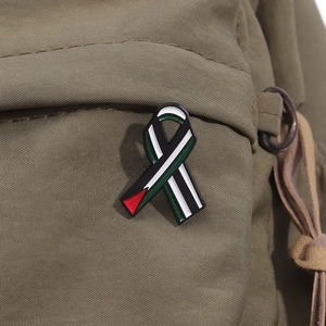 Macro shot of a ribbon-shaped enamel pin with Palestine flag colors on green canvas