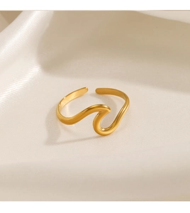 Detailed top view of a gold wavy stainless steel ring on elegant white silk fabric