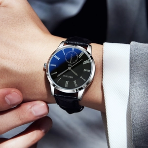 Men's business quartz watch with black roman dial and leather strap on a suit sleeve