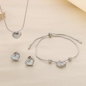 Three-piece silver titanium steel jewelry set with heart shell pendants on beige background