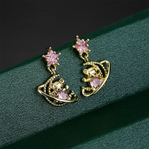 Macro shot of gold-plated insect earrings with pink gemstones on dark background