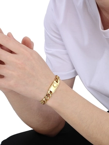 Close-up of a gold-colored curb chain bracelet with a square buckle clasp on male wrist